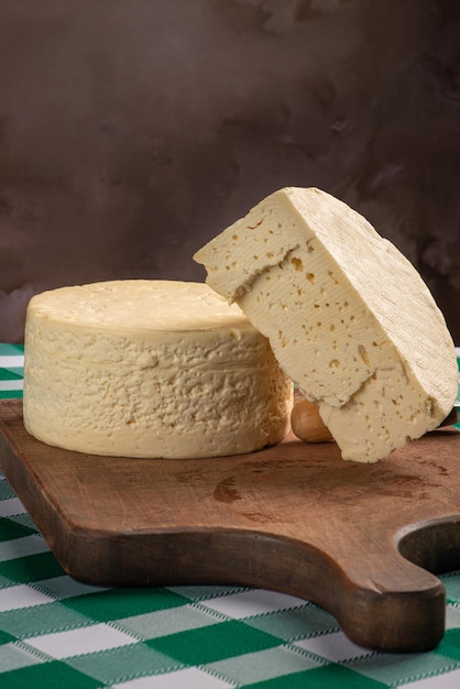 Fromage semi-durci du Brésil disposé sur une planche rustique sur une nappe à carreaux verts et blancs, mise au point sélective.