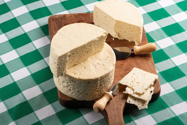 Fromage semi-durci du Brésil disposé sur une planche rustique sur une nappe à carreaux verts et blancs, mise au point sélective.