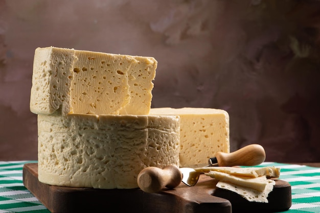 Fromage semi-durci du Brésil disposé sur une planche rustique sur une nappe à carreaux verts et blancs, mise au point sélective.