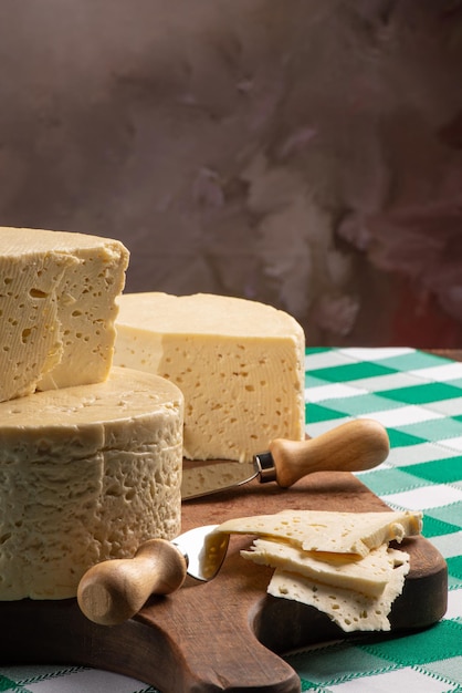 Fromage semi-durci du Brésil disposé sur une planche rustique sur une nappe à carreaux verts et blancs, mise au point sélective.