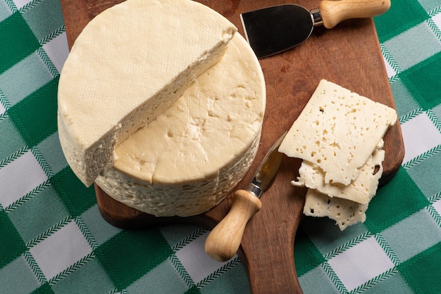 Fromage semi-durci du Brésil disposé sur une planche rustique sur une nappe à carreaux verts et blancs, mise au point sélective.