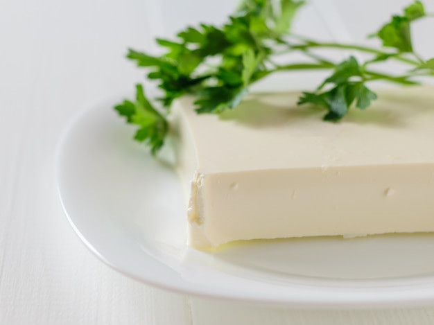 Fromage serbe avec des feuilles de persil sur un tableau blanc sur fond blanc.