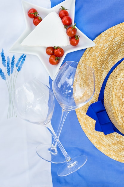 Fromage, tomate, verres sur une nappe bleue avec broderie