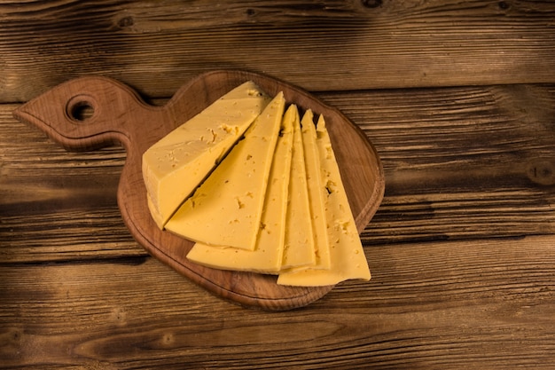 Fromage en tranches sur une planche à découper sur une table en bois