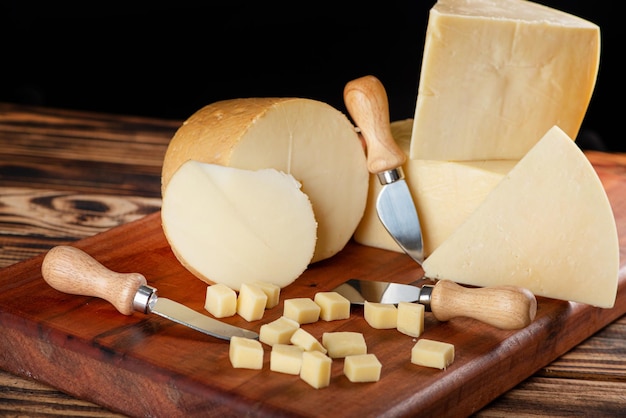 Fromages beaux morceaux de fromage et accessoires placés sur du bois rustique fond sombre mise au point sélective