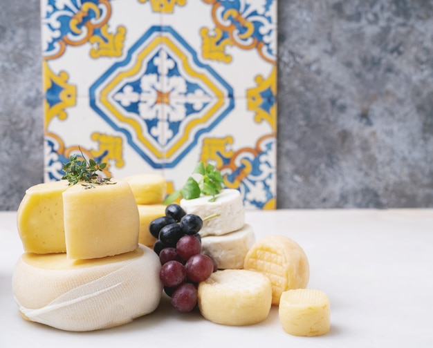 Fromages à pâte semi-molle traditionnels portugais sur le plateau, servis avec des raisins frais, du miel et des herbes. Vue de côté. Mise au point sélective.