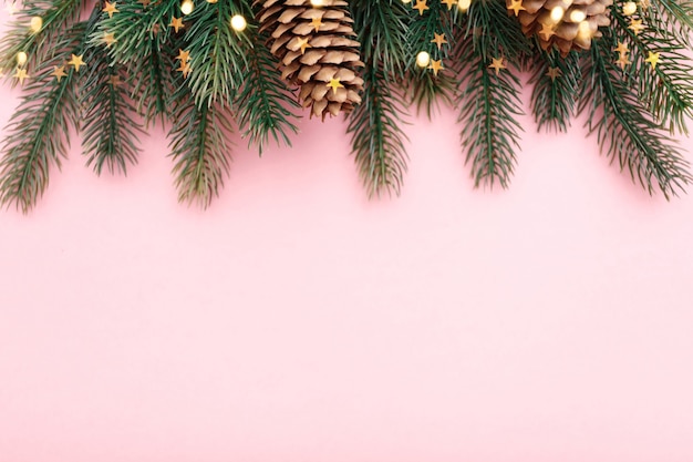 Frontière de Noël avec des branches de sapin, des cônes de conifères et des lumières dorées