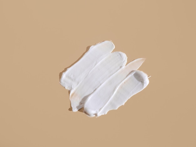 Frottis blanc de crème cosmétique sur fond beige Texture fond de teint crémeux isolé