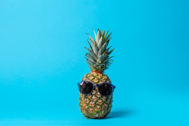 Fruit d'ananas mode hipster avec des lunettes de soleil sur fond bleu concept minimal