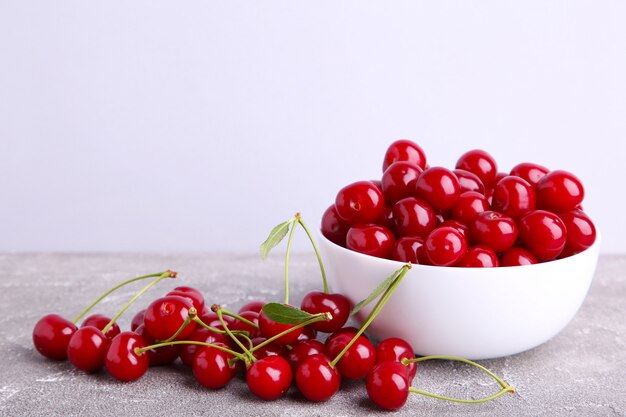 Fruit de cerise rouge frais dans un bol sur béton gris