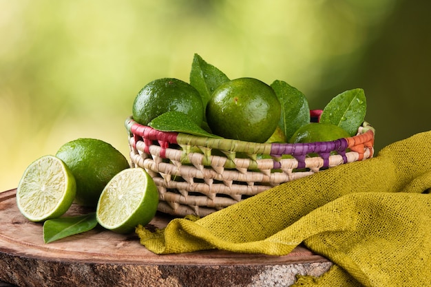 Fruit de citron vert dans un panier avec une surface verte floue.