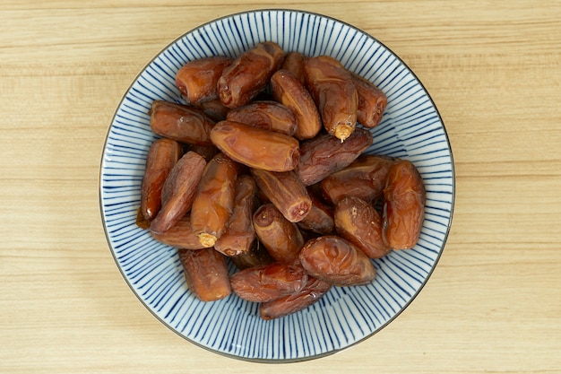 Fruit de dattes douces et séchées dans un bol et sur la table