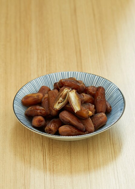 Fruit de dattes douces et séchées dans un bol et sur la table