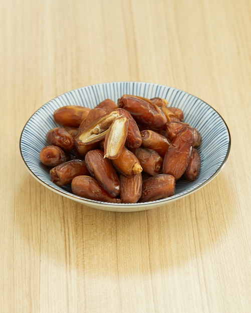 Fruit de dattes douces et séchées dans un bol et sur la table