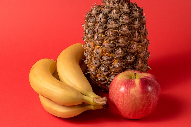 Fruit - fruit d&#39;ananas, pomme et banane sur fond rouge.