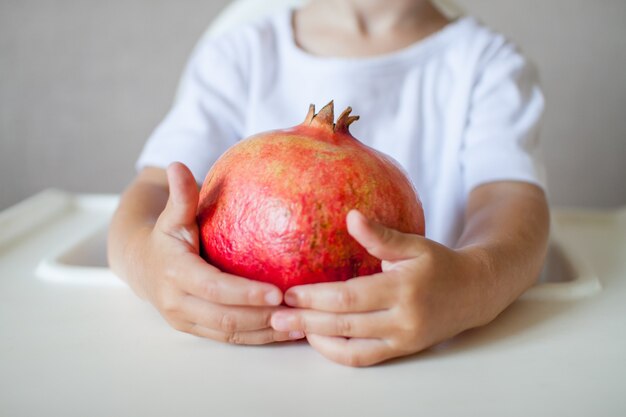 Fruit de grenade dans les mains d'un petit enfant en gros plan le symbole du rosh du nouvel an juif