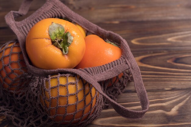 Fruit de kaki orange mûr.Close-up de kakis frais dans un sac de ficelle