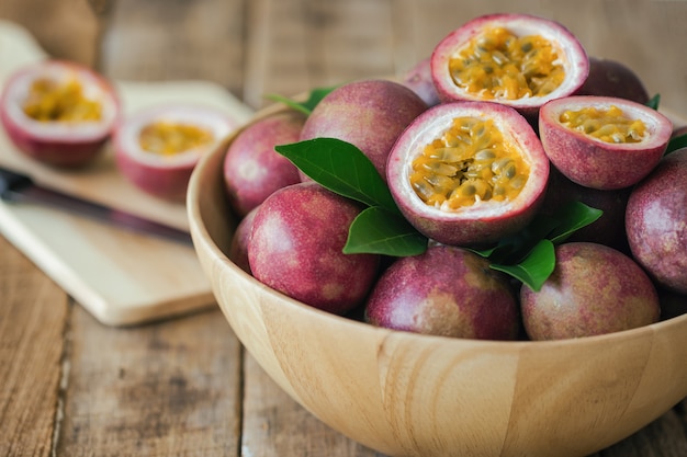 Fruit de la passion sur un bol en bois mis sur une table en bois en vue de côté pour le fond ou le papier peint.