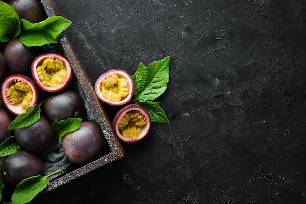 Fruit de la passion frais avec des feuilles dans une boîte en bois Fruits tropicaux Vue de dessus Espace libre pour le texte