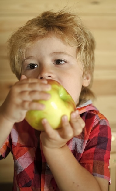 Fruit sans enfant gmo ou garçon blond heureux mangeant le petit-déjeuner aux pommes le matin des aliments sains pour la famille et de la vit...