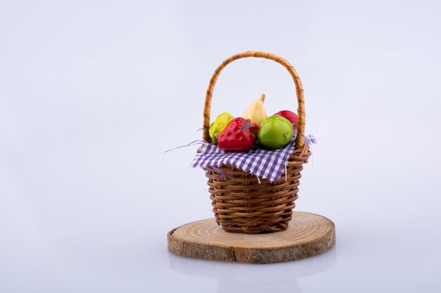 Fruits artificiels dans le panier en osier isolé sur fond blanc