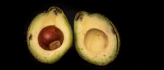 Fruits d'avocat tropicaux typiques coupés en deux sur fond noir