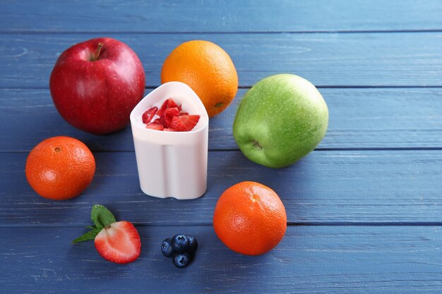 Fruits et baies autour d'une tasse en plastique de yaourtière sur fond de bois