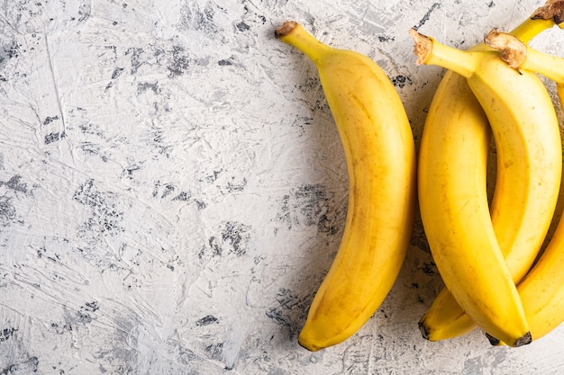 Fruits de banane sur une surface texturée blanche