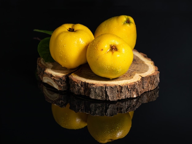 fruits de coing jaune mûr sur une coupe en bois sur fond noir