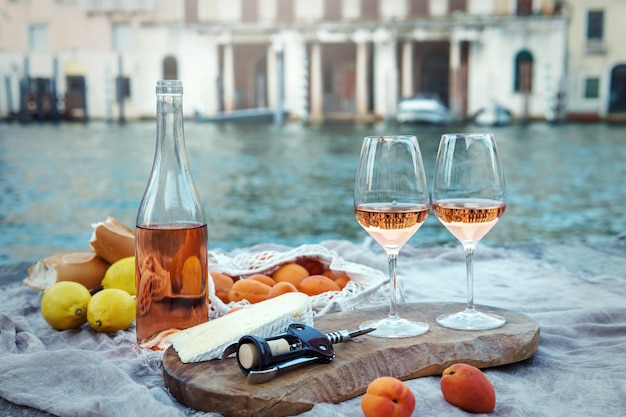 Fruits et collations au vin de rose sur la jetée en bois lors d'un pique-nique pittoresque sur le quai en bois