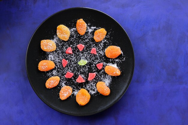 Fruits confits colorés et abricots secs sur une plaque noire sur fond bleu gros plan de nourriture végétarienne saine