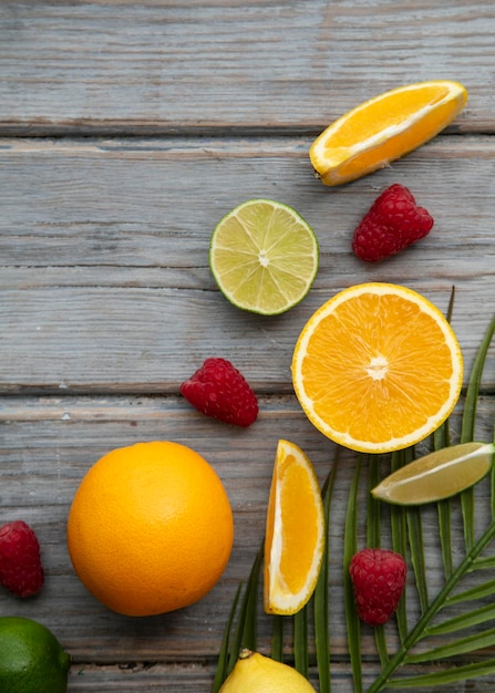 Fruits créatifs à plat orange citron vert et framboise sur le fond en bois