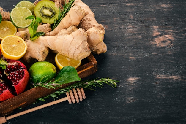 Fruits dans la boîte. Grenade, citron vert, gingembre, citron et menthe. Sur un fond en bois. Vue de dessus. Copiez l'espace.