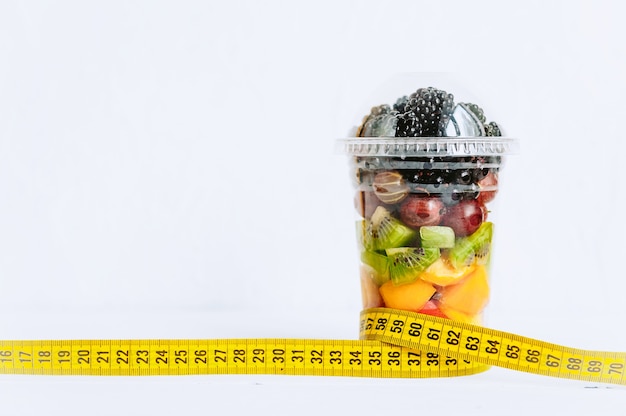 Fruits dans un verre, un ruban pour mesurer le corps. Concept de nutrition saine et de perte de poids