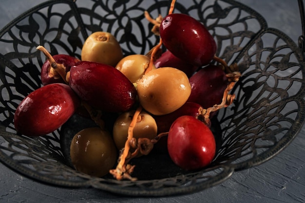 Fruits de dattes crues rouges et jaunes ou Kurma Muda (Ruthob) sur panier vintage au-dessus de fond rustique.