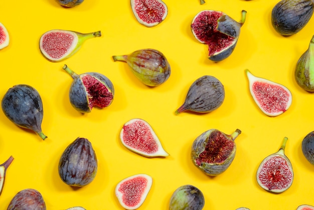 des fruits entiers et des tranches de figues sont étalés sur une surface jaune. figue fruits frais