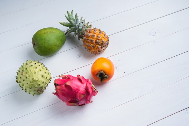 Fruits d'été frais exotiques sur blanc. Fruit du Dragon, ananas, kaki, mangue, annona cherimola à plat avec espace de copie gratuit.