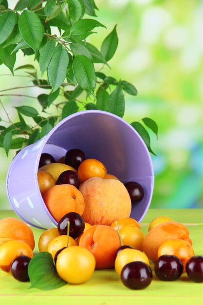 Fruits d'été lumineux dans un seau sur une table en bois sur fond naturel