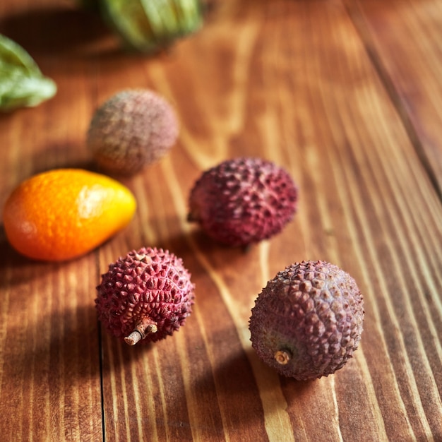 Fruits exotiques d'été avec des ingrédients frais et juteux - litchi, kumquat sur un fond en bois, place pour le texte. Concept de régime alimentaire sain.