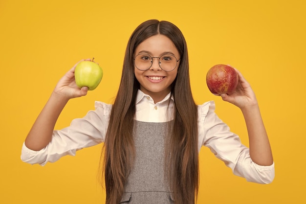 Des fruits frais Une adolescente tient des pommes sur un fond de studio isolé jaune Nutrition de l'enfant Une fille heureuse fait face à des émotions positives et souriantes