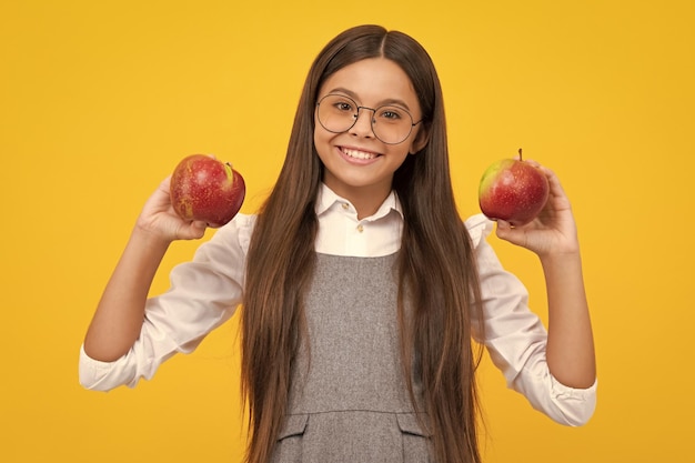 Des fruits frais Une adolescente tient des pommes sur un fond de studio isolé jaune Nutrition de l'enfant Une fille heureuse fait face à des émotions positives et souriantes