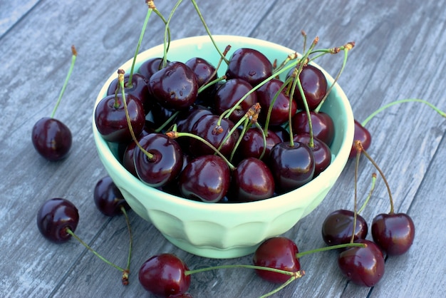 Fruits frais de cerise dans un bol sur un fond en bois.