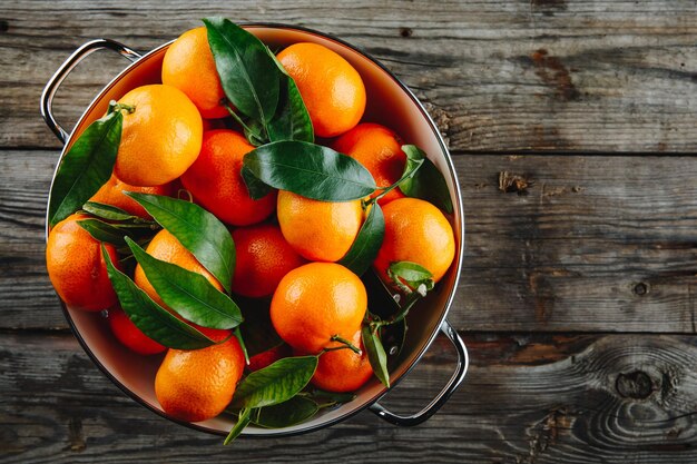 Fruits frais de clémentines mandarines ou mandarines avec des feuilles sur fond rustique en bois