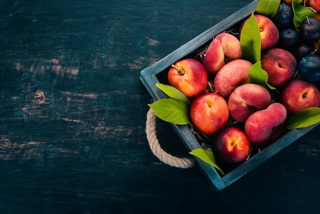 Fruits frais dans une boîte en bois Abricot pêche prune nectarine Sur un fond en bois Vue de dessus Espace libre pour votre texte