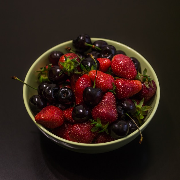 Fruits frais de fraises et de cerises dans une tasse