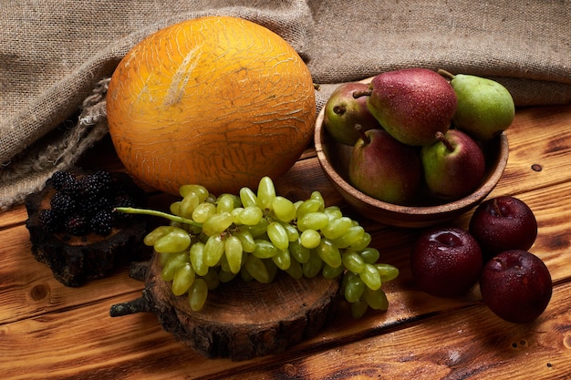 fruits frais avec melon, raisins, prunes, poires et mûres sur une table en bois