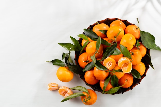 Fruits frais d'oranges mandarines avec des feuilles dans une boîte en bois, vue du dessus.