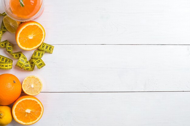 Fruits frais avec ruban à mesurer sur fond de bois blanc vue de dessus