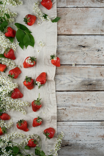 Fruits de fraises d&#39;été et fleurs de cerisier des oiseaux au bas sur le textile et le bois