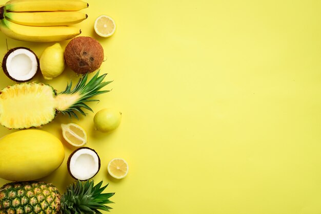 Fruits jaunes biologiques frais sur fond ensoleillé. Concept monochrome avec banane, noix de coco, ananas, citron, melon.